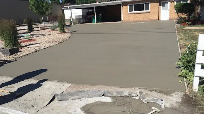 A concrete driveway is being built in front of a house.