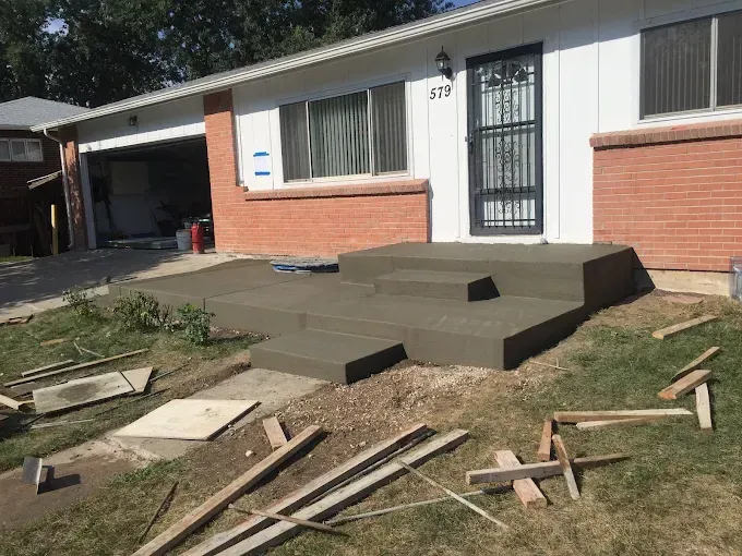 A house with concrete steps being built in front of it.