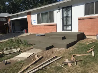 A house with concrete steps being built in front of it.