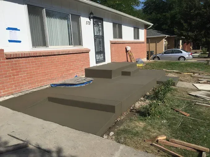 A concrete walkway is being built in front of a house.