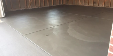 A concrete floor in a garage with a brick wall.
