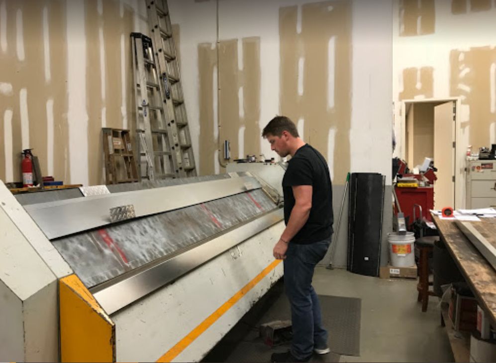 A man is standing in front of a machine in a workshop.