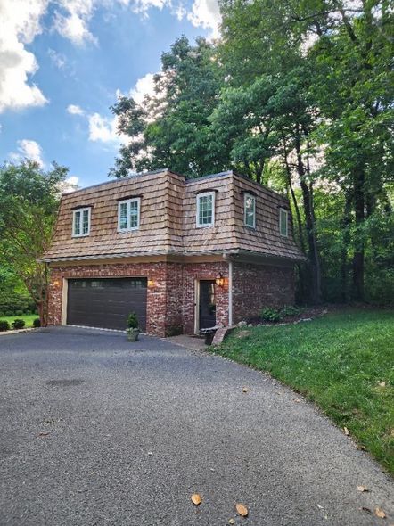 A large brick house with a garage and a driveway in front of it.