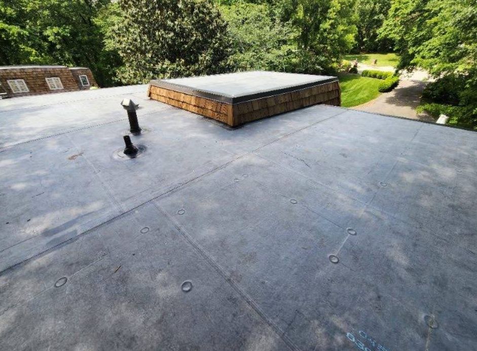 A roof with a wooden box on top of it and trees in the background.