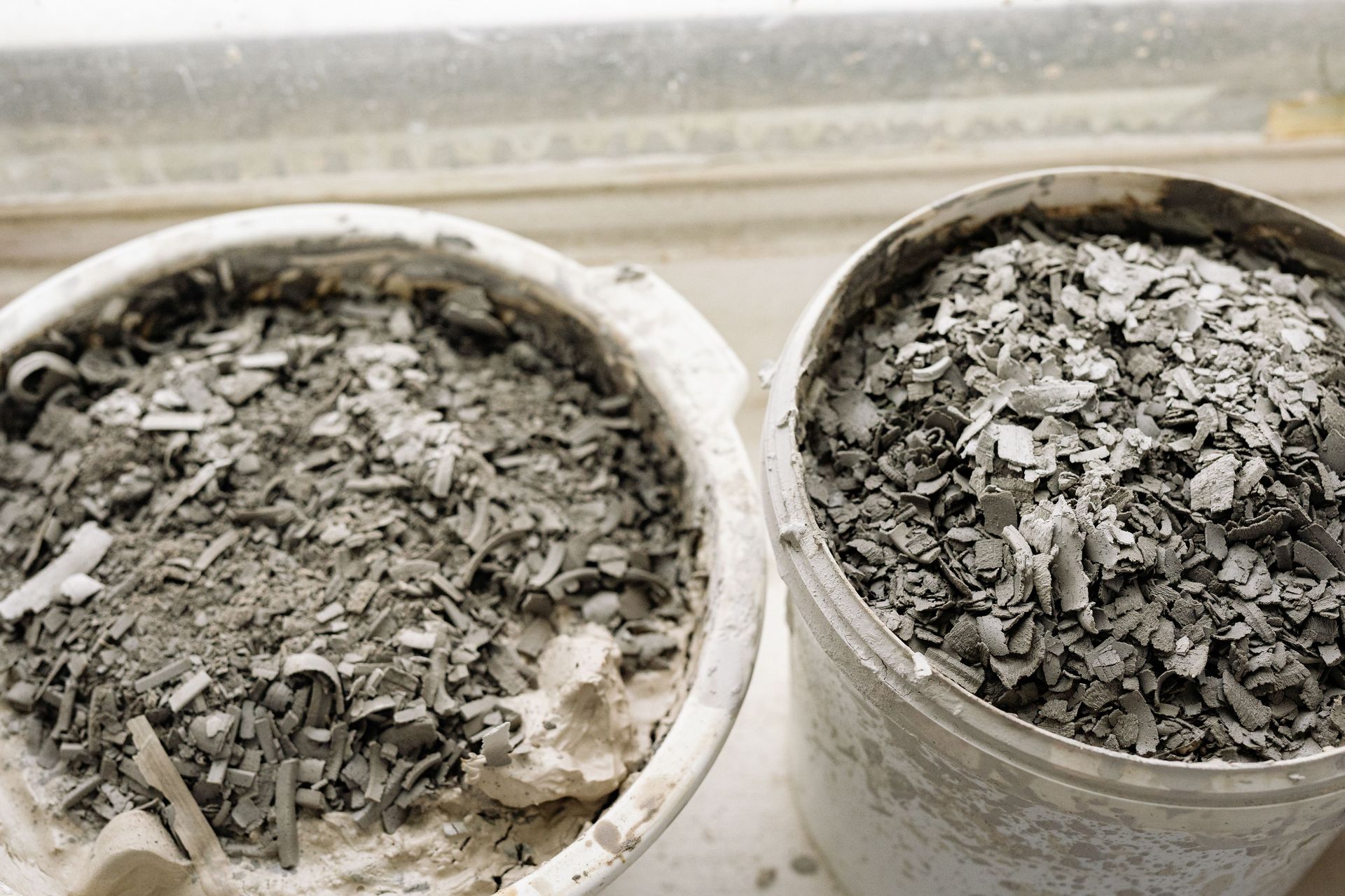 Two white cups filled with gray ash or debris on a light surface