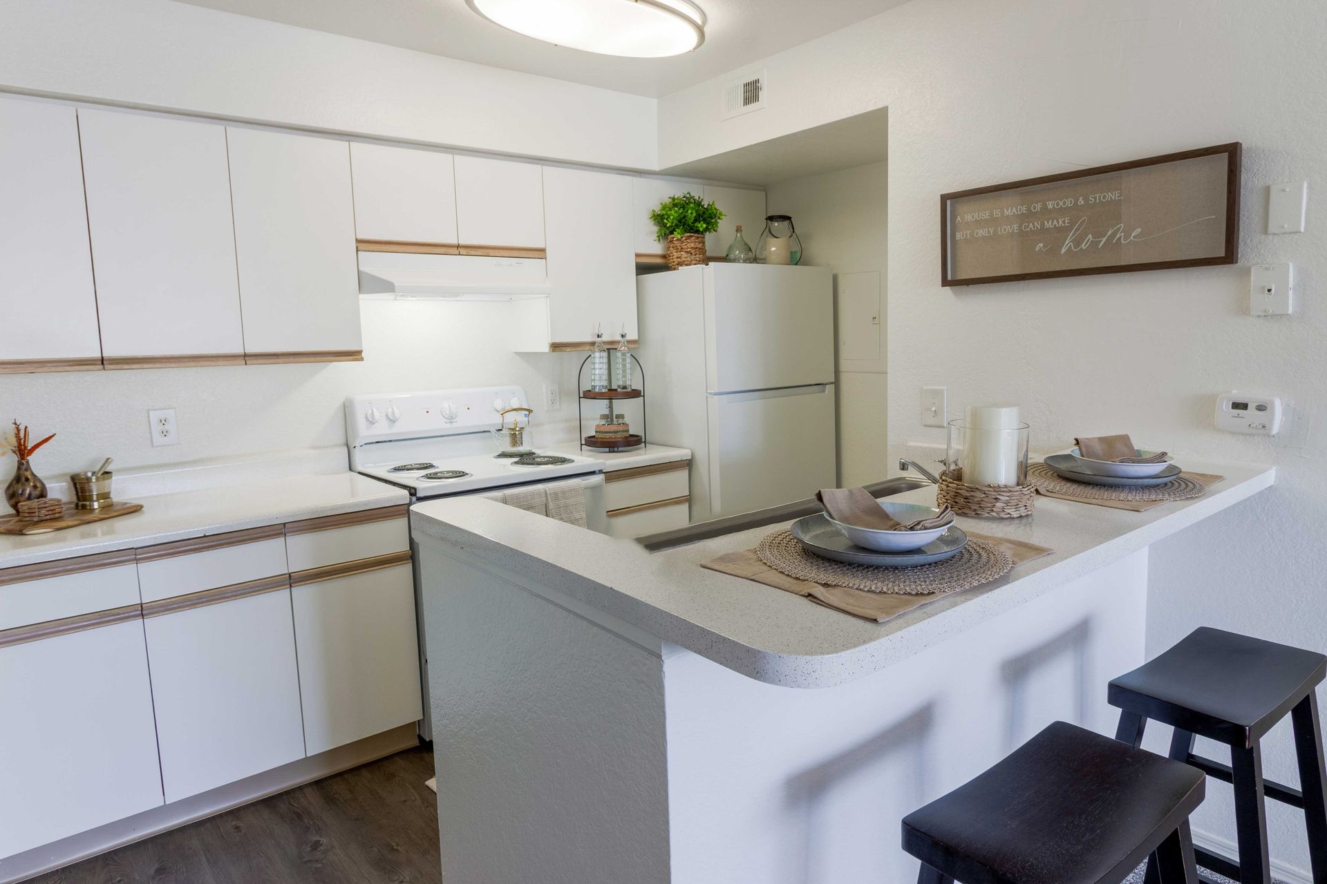 White kitchen with a breakfast bar and stools at The Point at Naples in Naples, FL.