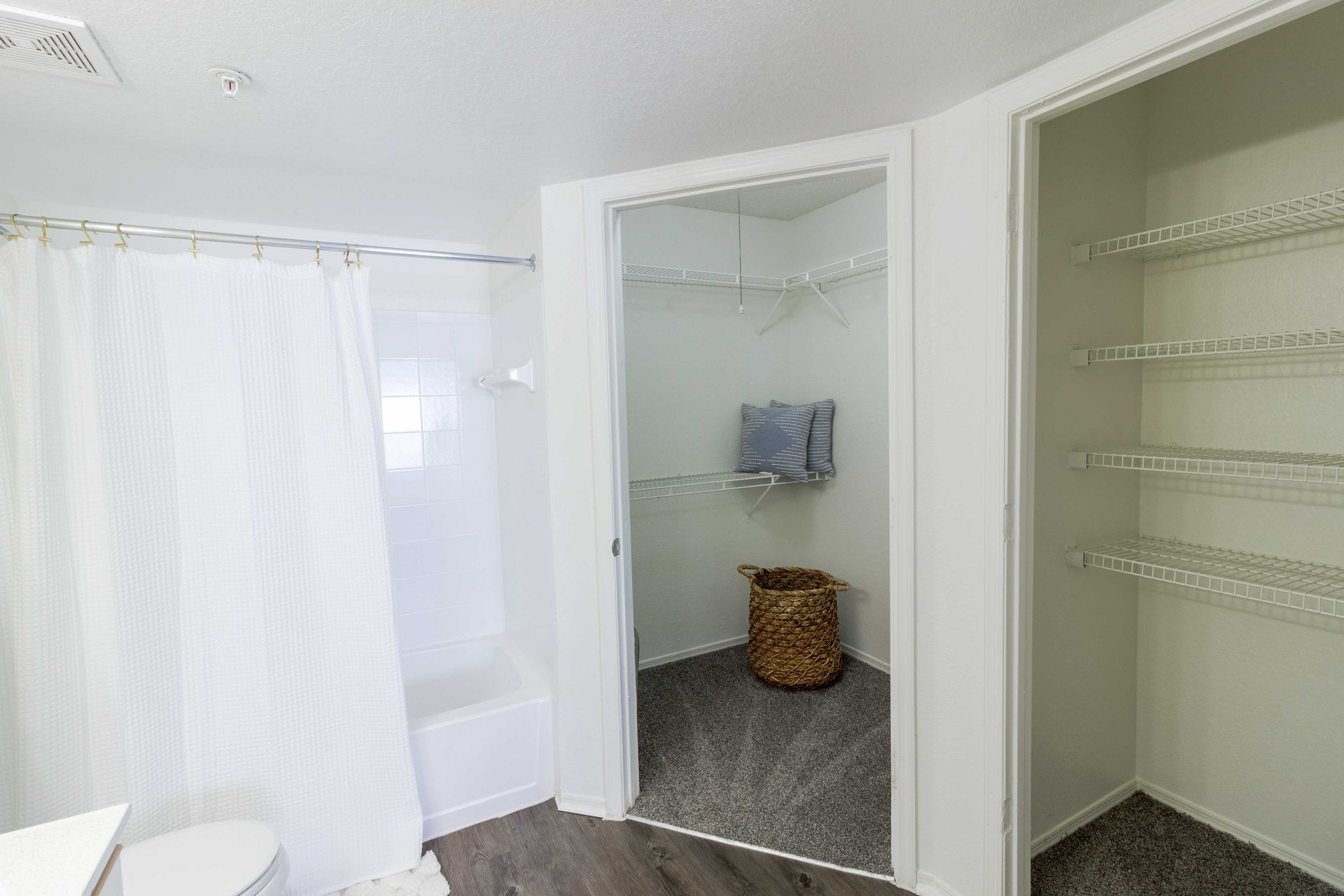 Bathroom with a shower, linen closet, and storage closet, white walls, grey floors at The Point at Naples in Naples, FL.