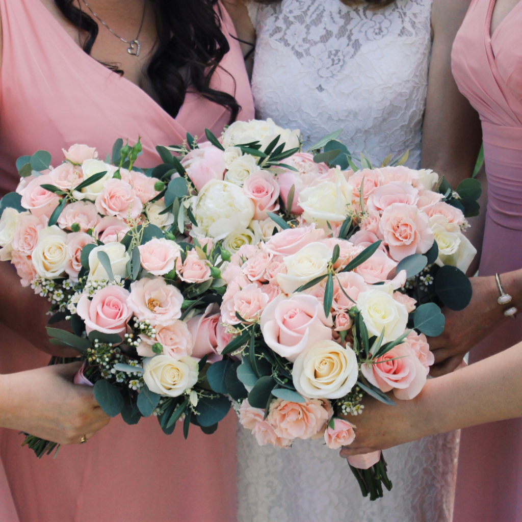 A bride and her bridesmaids are holding bouquets of pink and white flowers