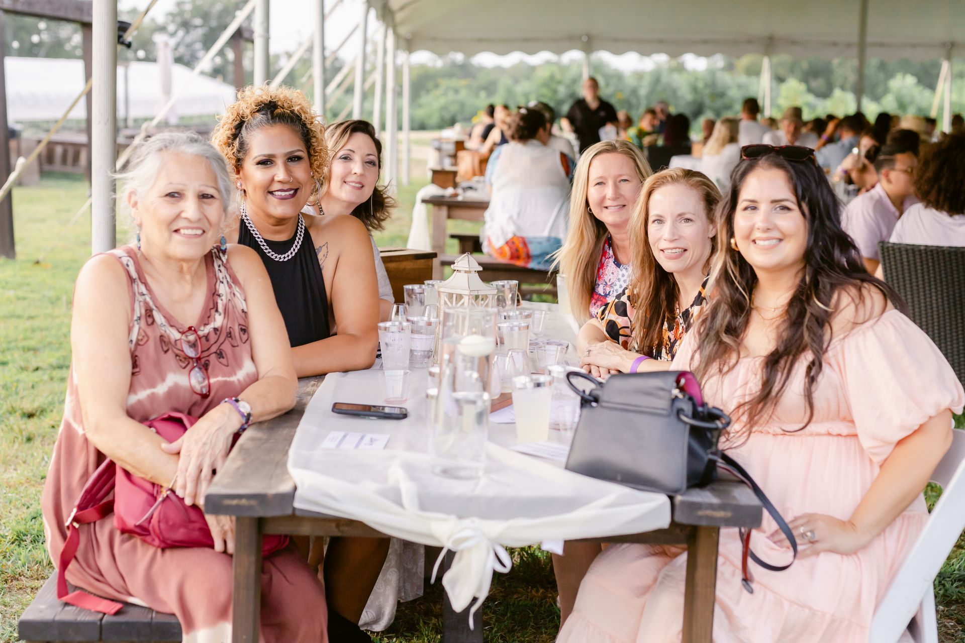 A group of women are sitting at a table under a tent.