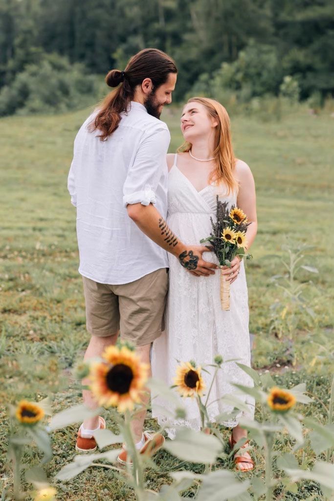 A man and a woman are standing in a field of sunflowers.