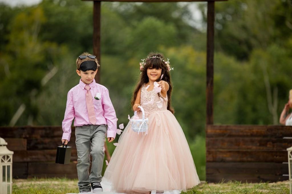 A flower girl and ring bearer are walking down the aisle at a wedding.
