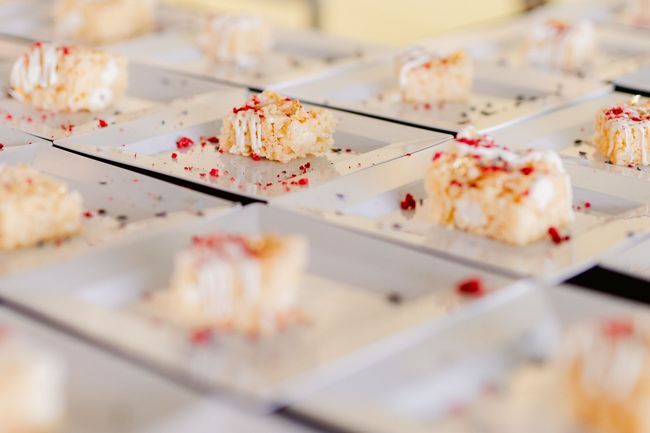 A row of white plates filled with desserts on a table.