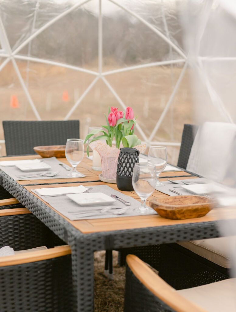 A table with plates , glasses , and a vase of flowers on it.