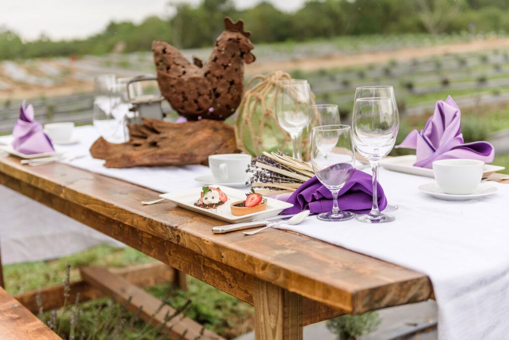 A wooden table with plates of food and wine glasses on it.