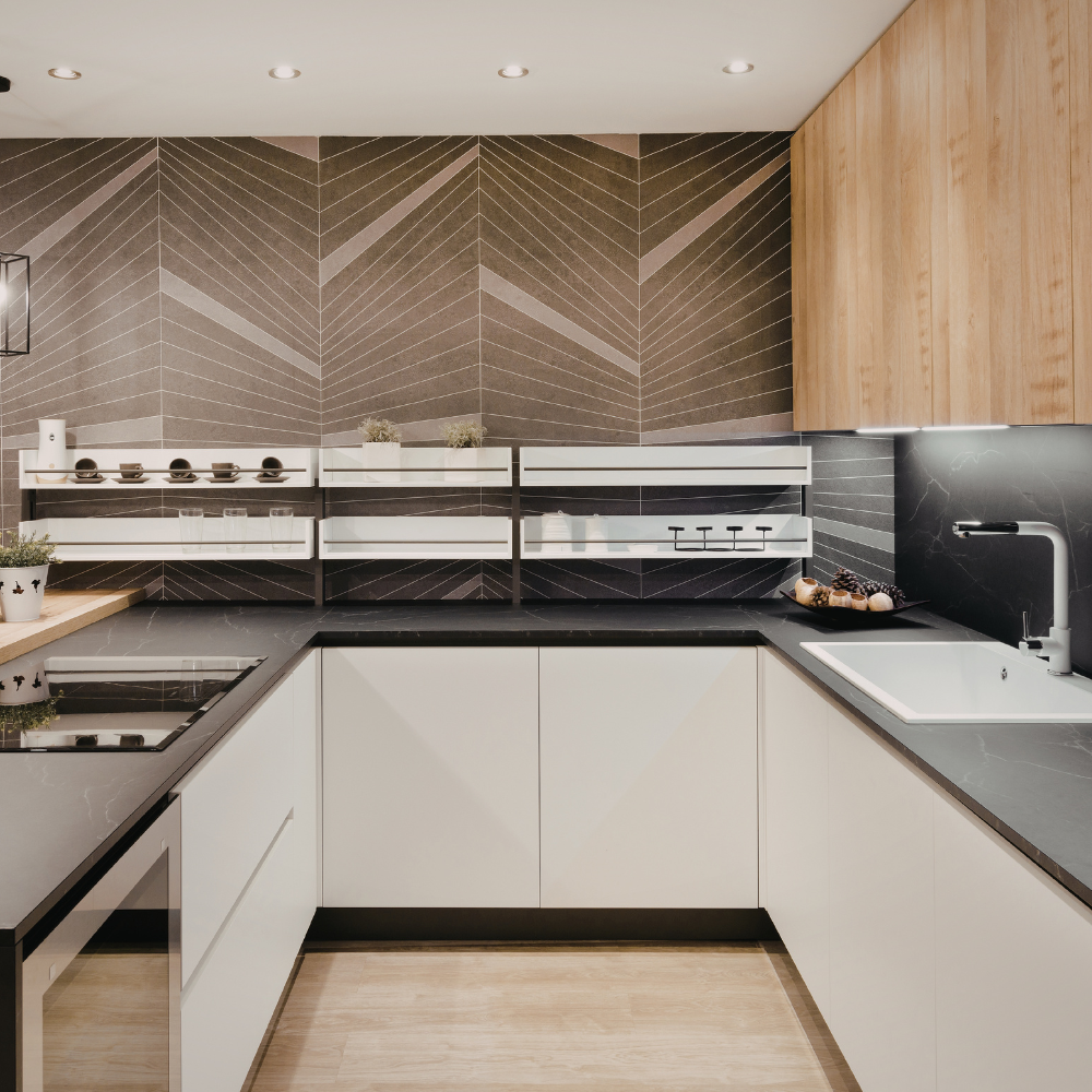 Modern U-shaped kitchen with white cabinets, dark gray countertops, light wood wall cabinets, and geometric tile backsplash.