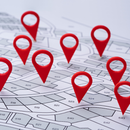 Several red map pins are placed on different plots of a printed land survey map.