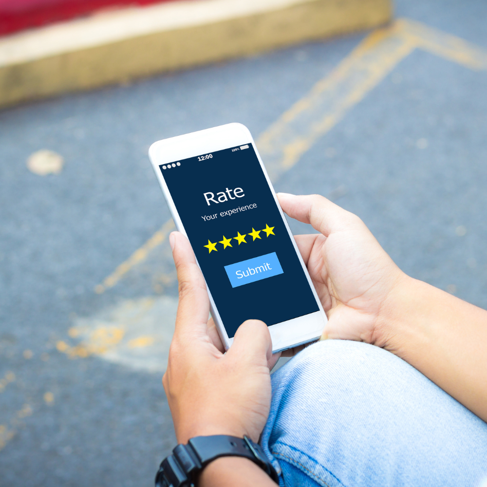A person holds a smartphone displaying a five-star rating screen with a submit button, set against a blurry urban background.