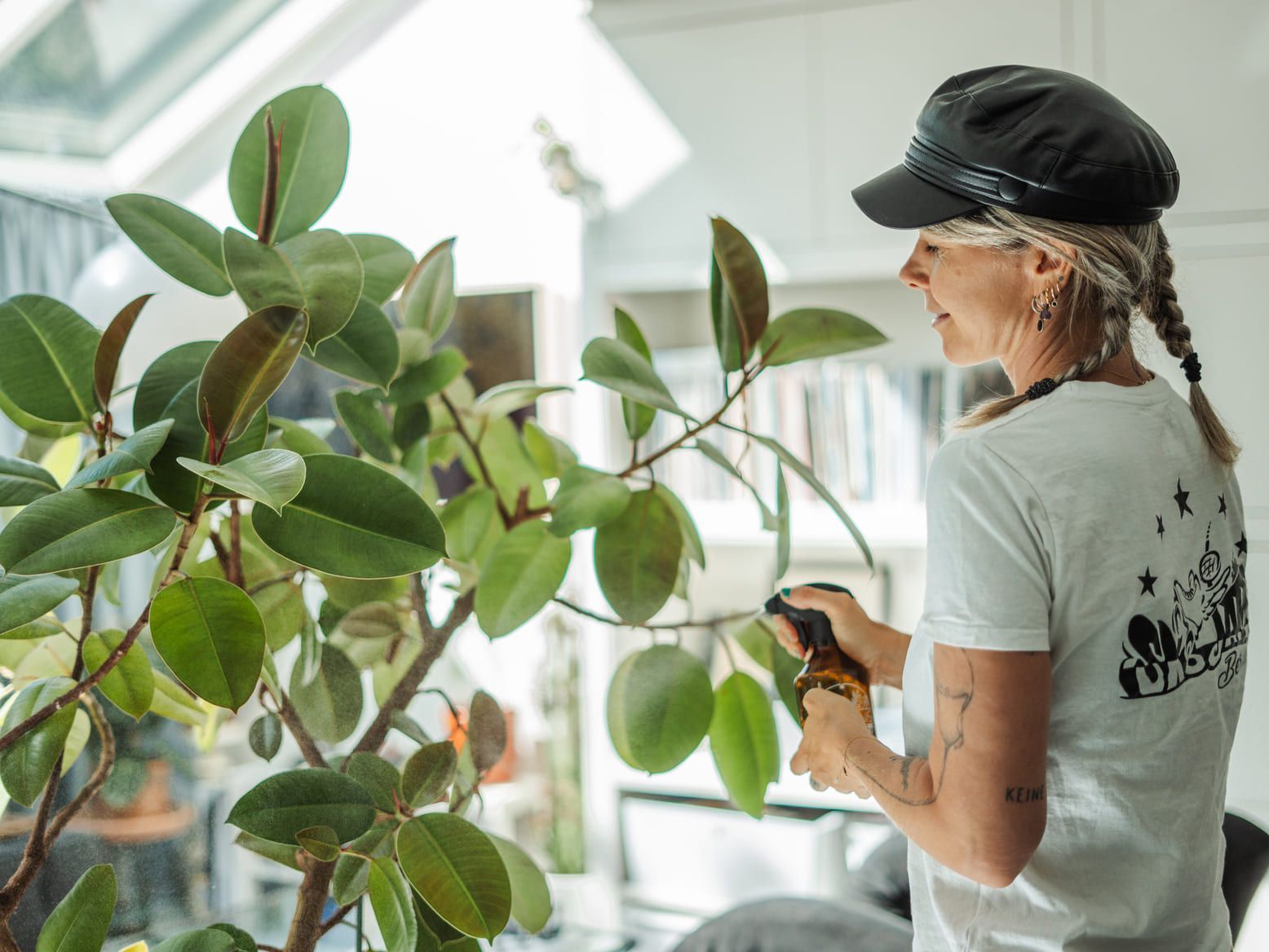 A woman is watering a potted plant in a living room.