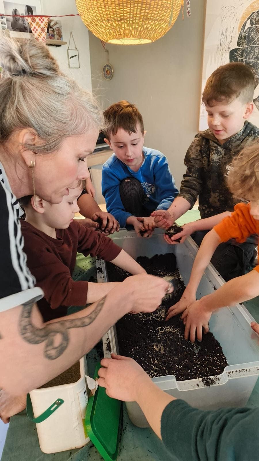 A group of children at a childrens birthday partyt around a table playing with soil.