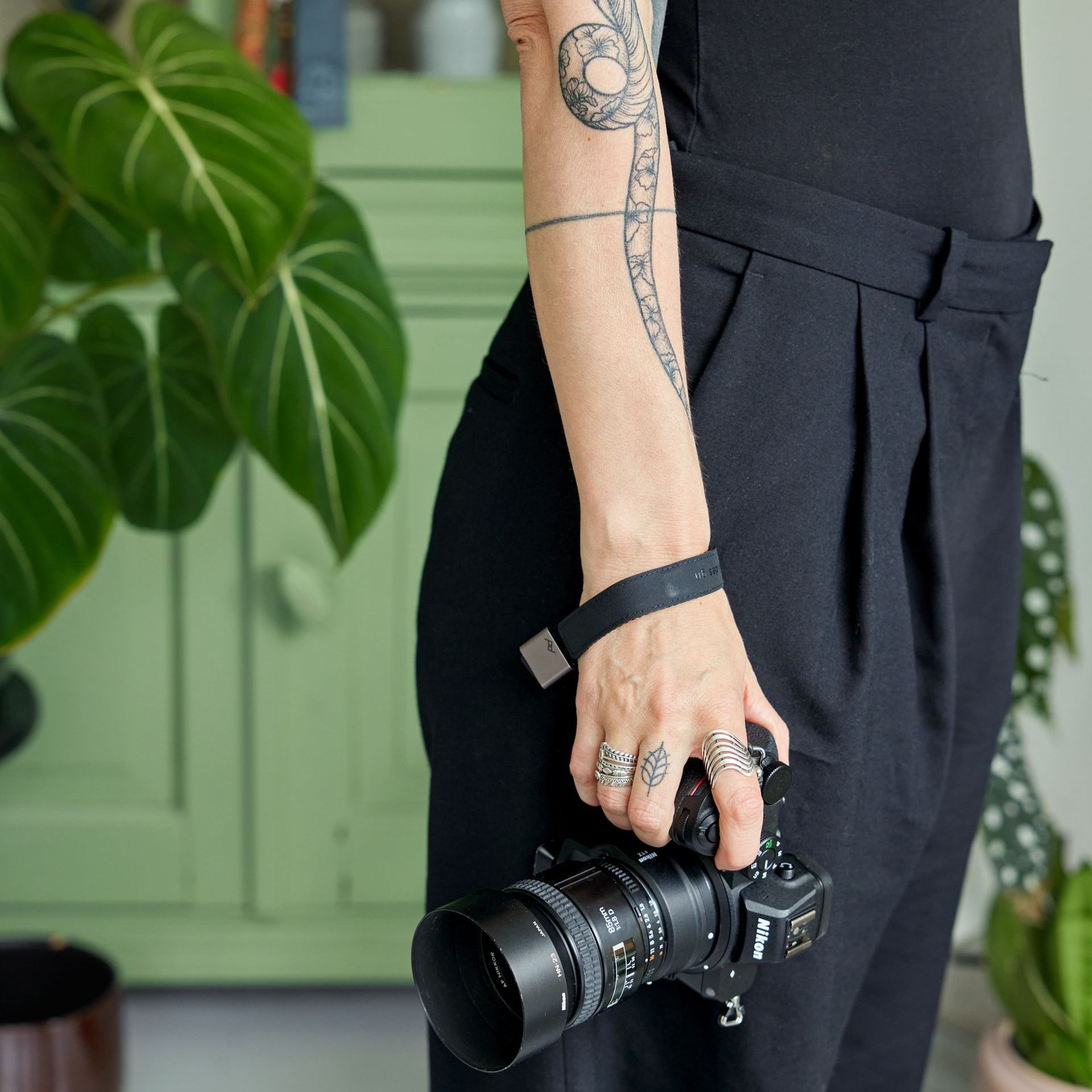 A woman with a tattoo on her arm is holding a camera