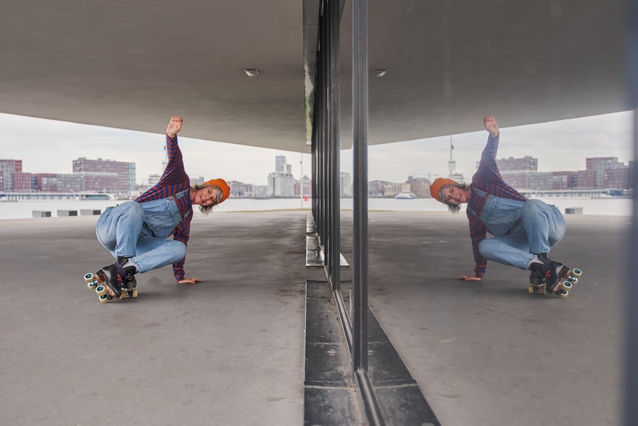a woman doing roller skate stunts in front of a window mirror .