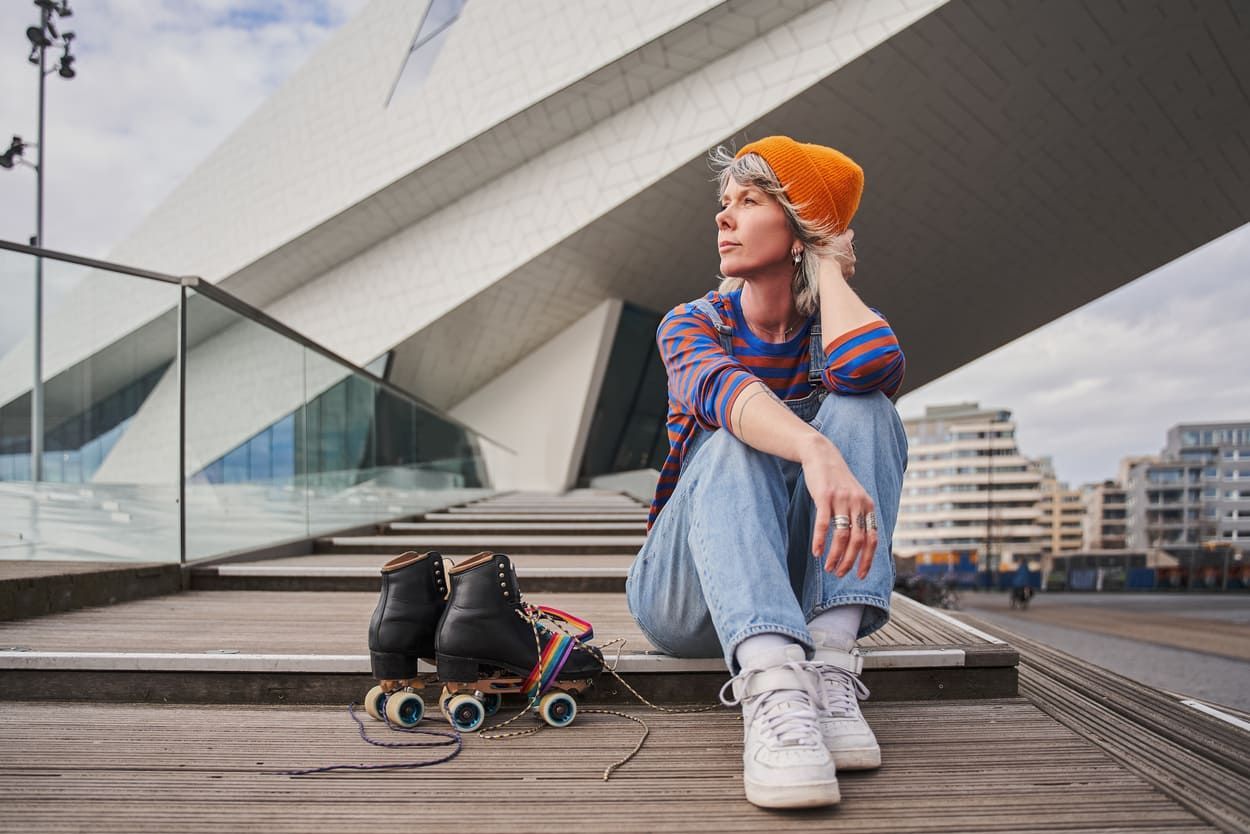 A woman is sitting on a set of stairs next to her roller skates.