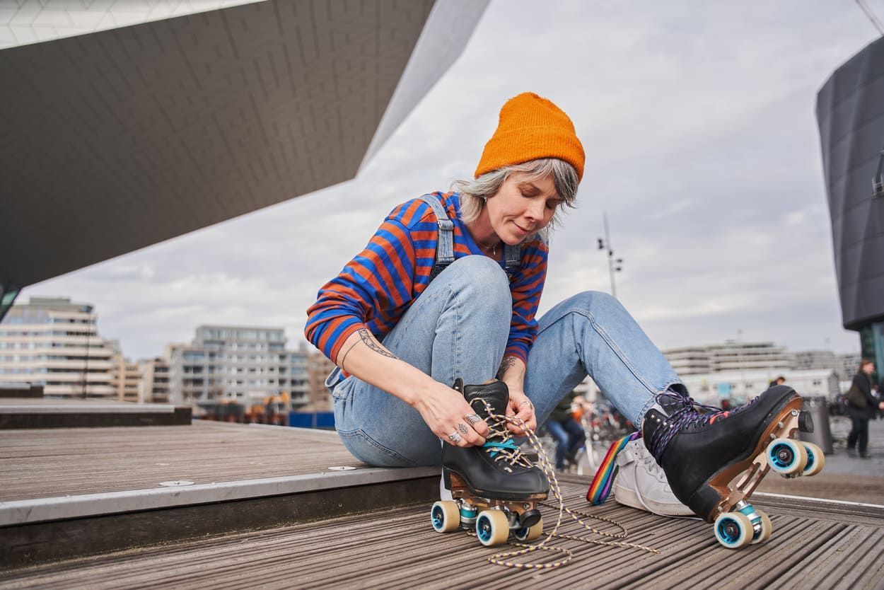 a woman is sitting on the steps tying her roller skates .
