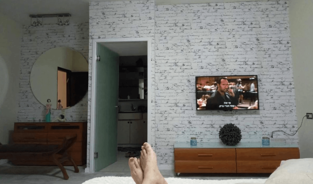 A person is laying on a bed in front of a television.