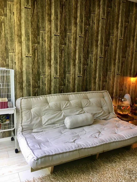 A white futon couch is sitting in a living room next to a bird cage.