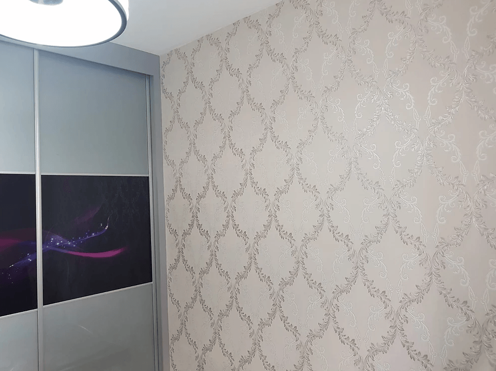 A bedroom with a sliding wardrobe and a purple wallpaper on the wall.