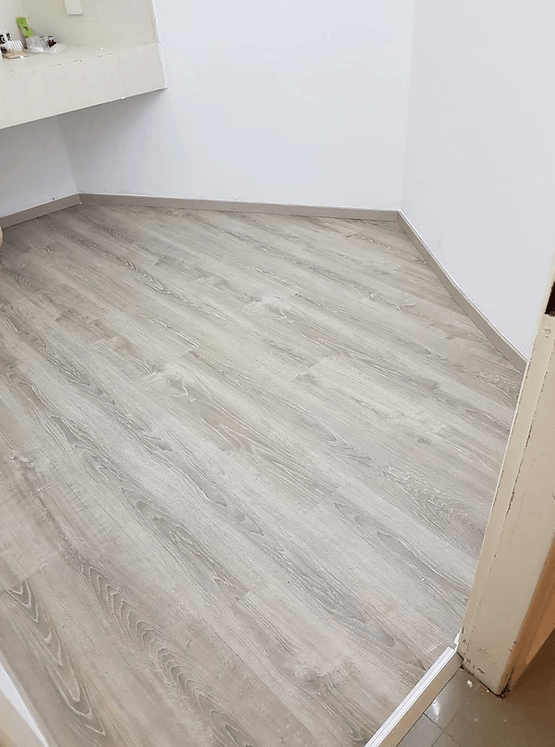 A room with a wooden floor and a white wall.