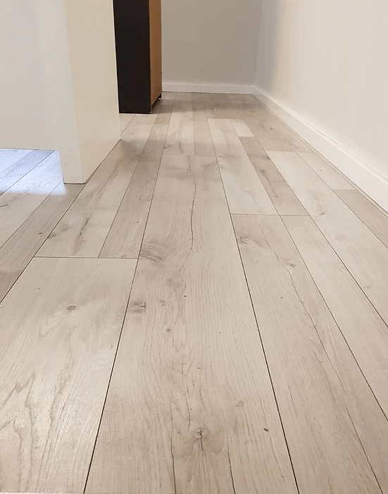 A hallway with a wooden floor and a white wall.