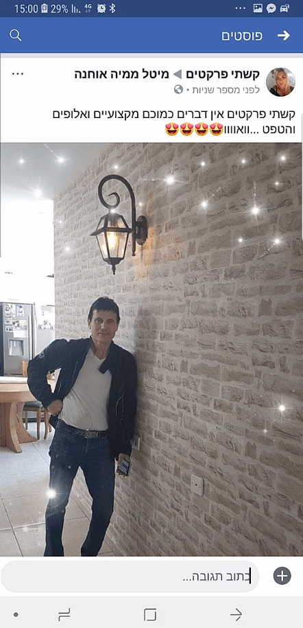 A man is standing in front of a brick wall.