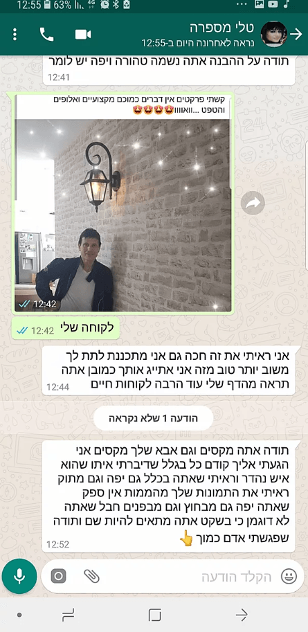 A man is standing in front of a brick wall talking on a cell phone.