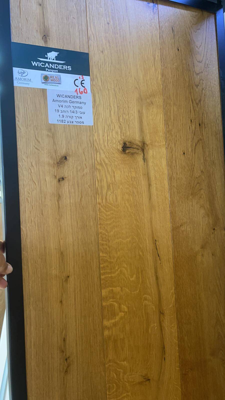 A person is holding a piece of wood with a sticker on it.