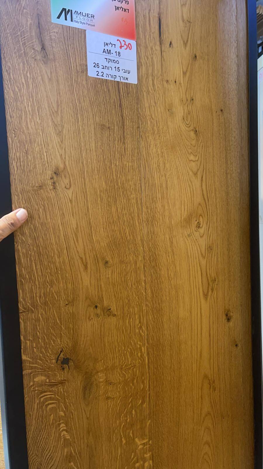 A person is pointing at a piece of wood with a label on it.