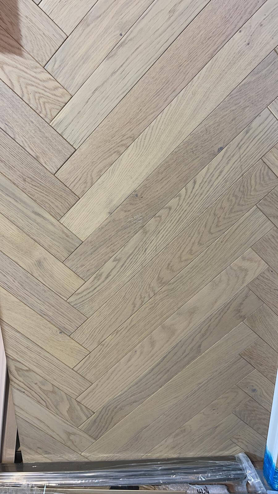 A close up of a wooden floor with a herringbone pattern.