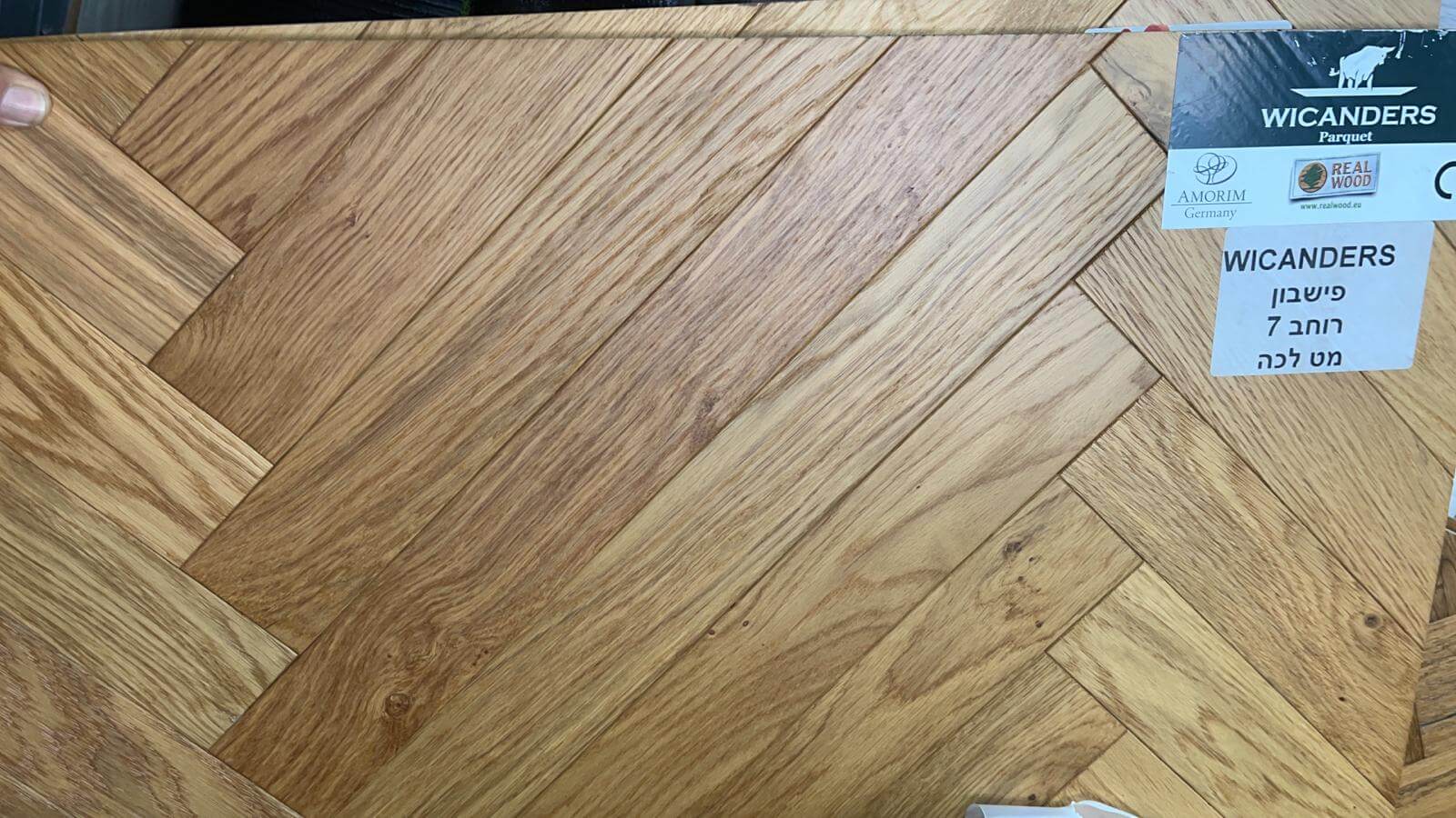 A person is holding a piece of wood with a herringbone pattern.