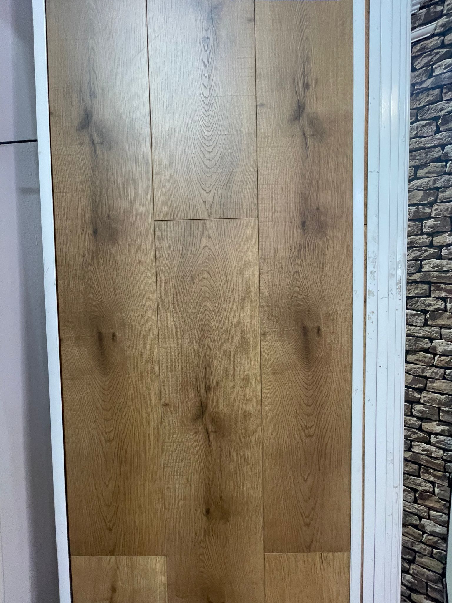 A close up of a wooden door with a brick wall in the background.