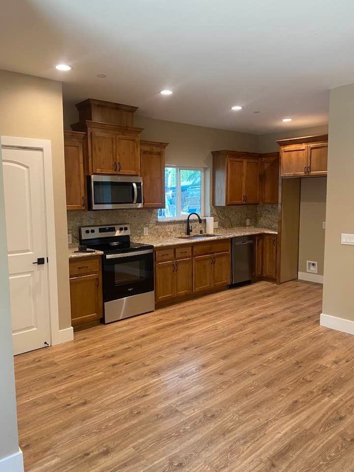 Kitchen with light wood cabinets, stainless steel appliances, granite countertops, and wood floors.