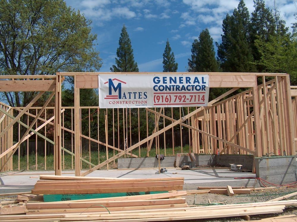 Construction site with wood framing; banner for Mattes General Contractor.