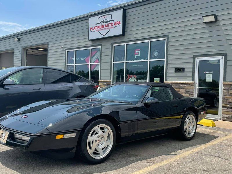 Black Corvette convertible parked outside a detailing shop.