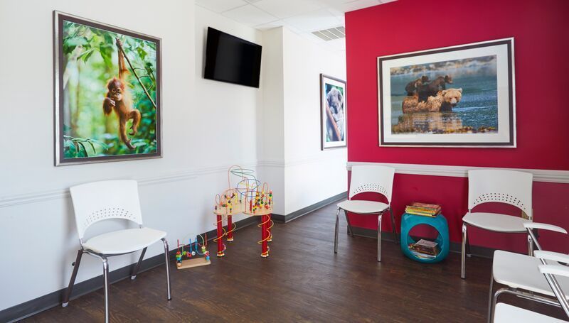 A waiting room with chairs and a picture of a monkey on the wall.