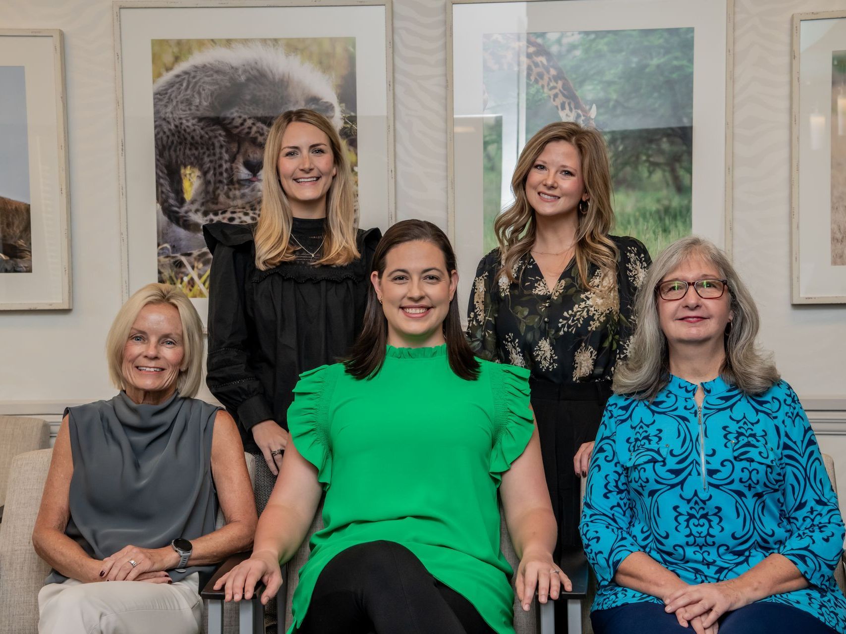 A group of women are posing for a picture while sitting in chairs.