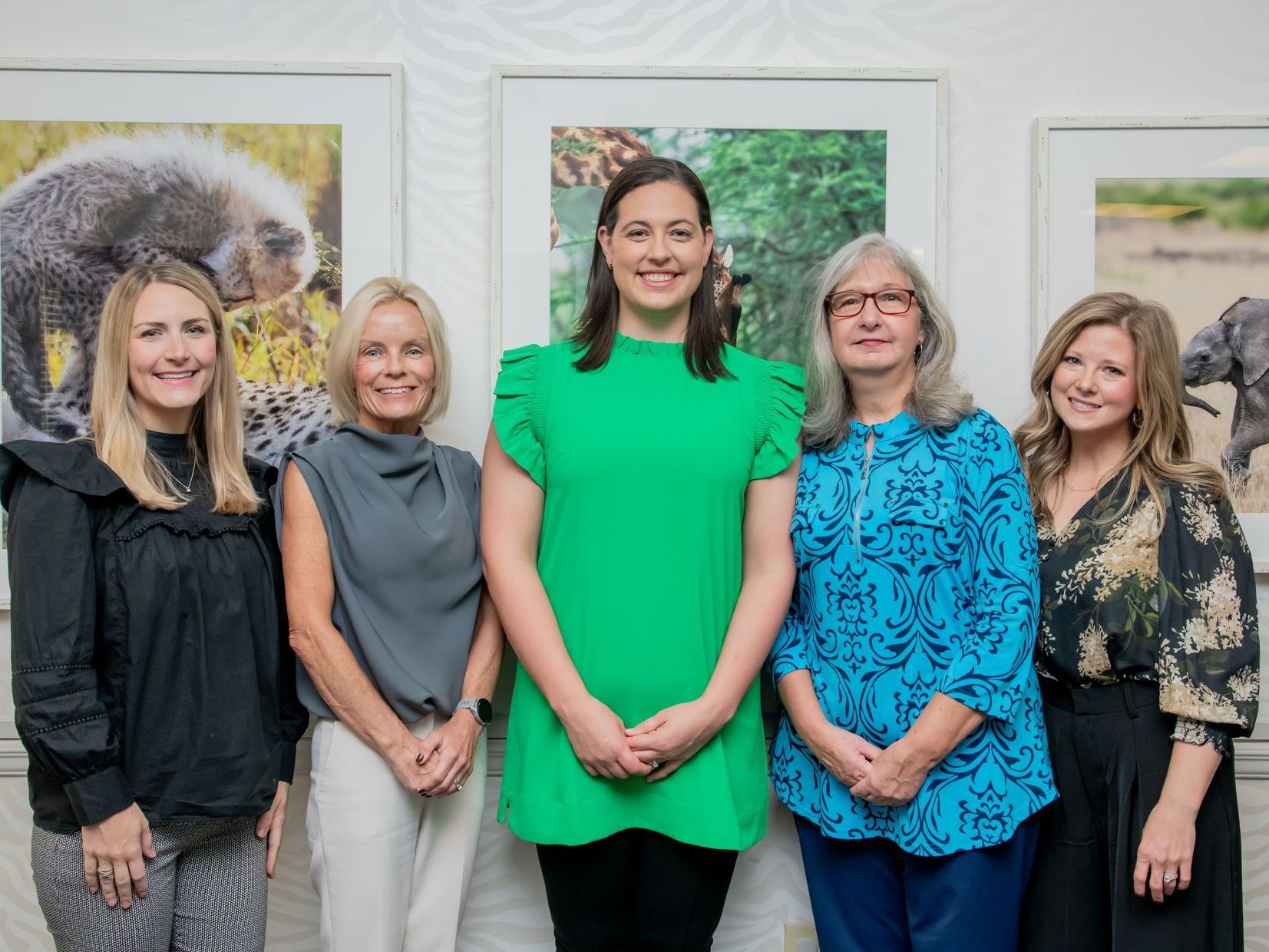 A group of women are posing for a picture in front of pictures of animals.