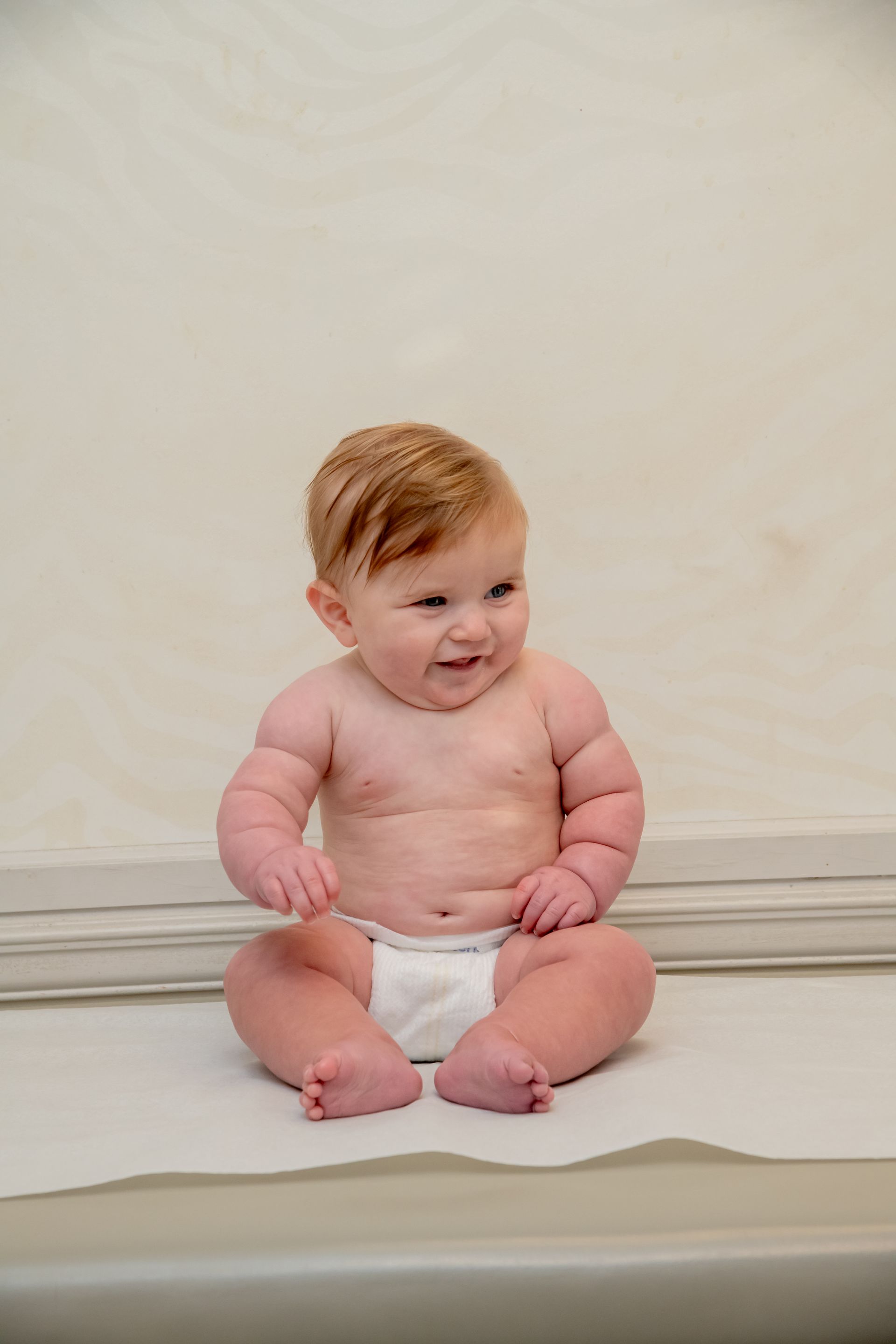 A baby in a diaper is sitting on a table.