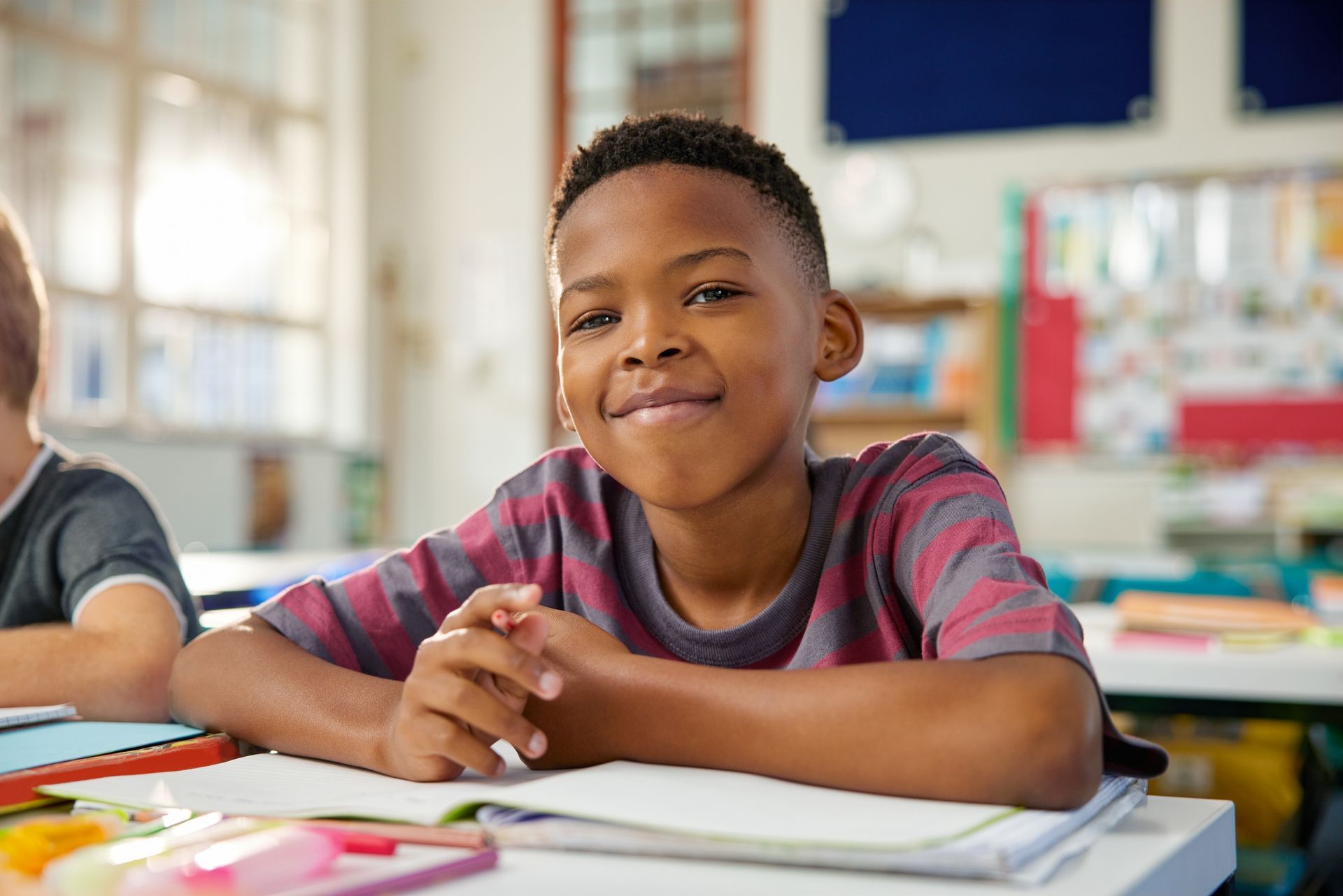 Smiling boy at desk in classroom.