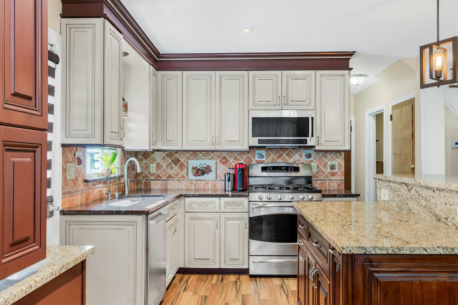 Bright kitchen with cream cabinets, stainless steel appliances, granite counters, and wood trim