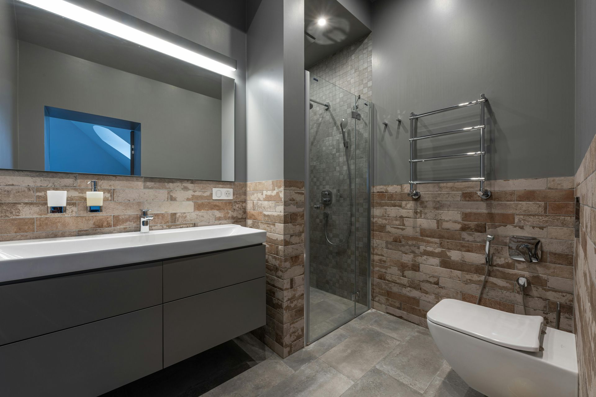 Modern bathroom with double vanity, large mirror, walk-in shower, and wall-mounted toilet.