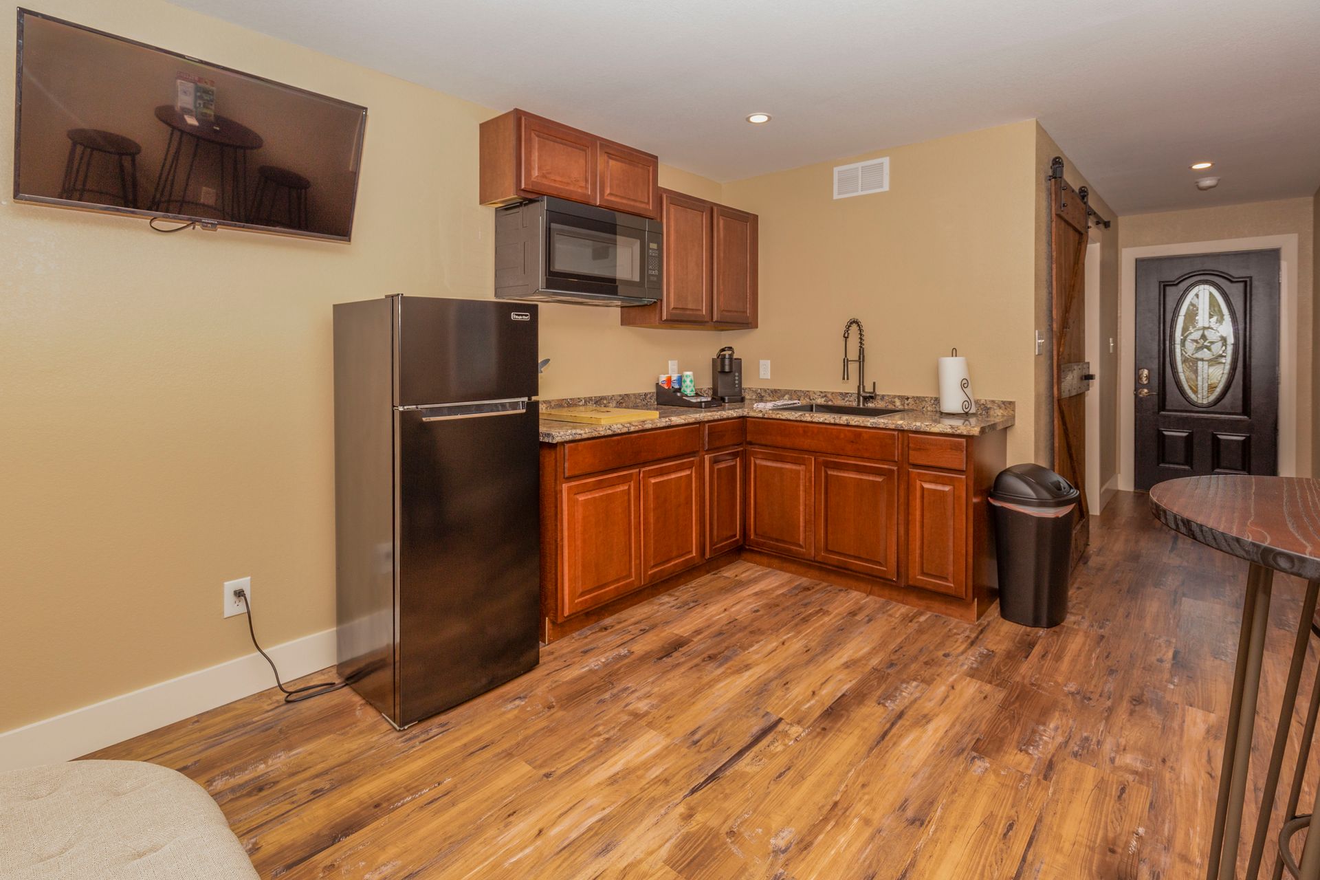 A kitchen with a refrigerator , microwave , sink and television.